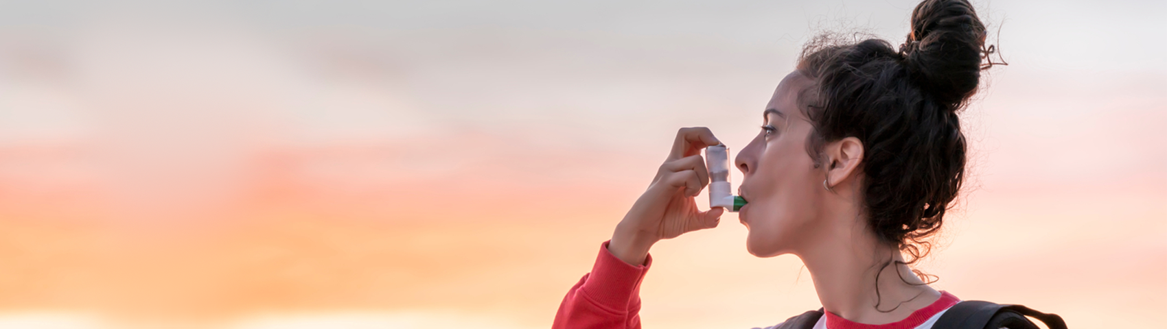  Millennial woman takes a break from her day hike in the lake to use her asthma inhaler